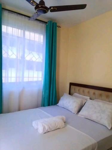 a bedroom with a bed with two pillows and a window at Leo's Enchanting homes in Mombasa