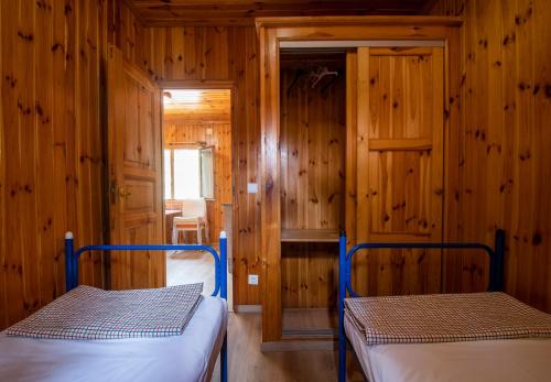 two beds in a room with wooden walls at Camping Rural Ria de Arosa 2 in Ribeira