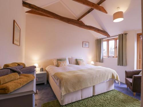 a bedroom with a large bed and a chair at Little Owl Cottage in Saxmundham
