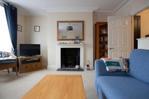 a living room with a blue couch and a fireplace at Elegant 2 bed in the heart of Falmouth - sleeps 4 in Falmouth