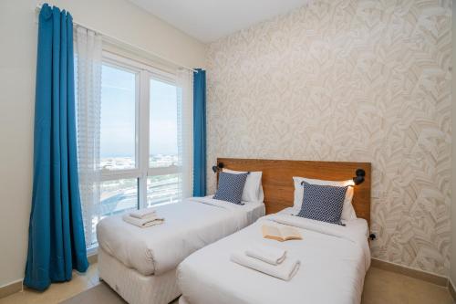 two beds in a room with a window at Tecom-Barsha Heights Retreat 2BR Stroll to Metro in Dubai