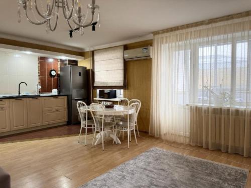 a kitchen with a table with chairs and a refrigerator at Квартира in Aktobe