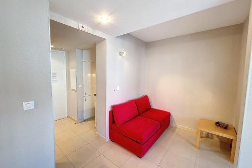 une chaise rouge dans une chambre avec une table dans l'établissement HENRI CAMILLE REAL ESTATE - Rouaze 2 -Studio à 50m center, à Cannes