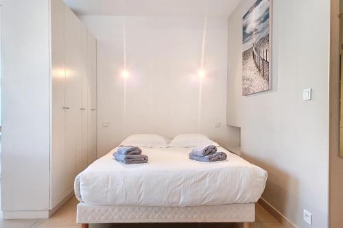 une chambre blanche avec un lit avec des serviettes dessus dans l'établissement HENRI CAMILLE REAL ESTATE - Rouaze 2 -Studio à 50m center, à Cannes
