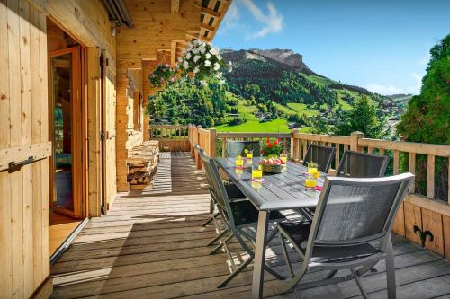 una terrazza in legno con tavolo e sedie. di Cristal des Neiges La Clusaz - OVO Network a La Clusaz