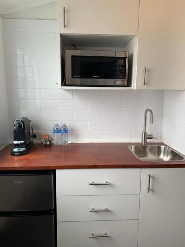 eine Küche mit einer Spüle und einer Mikrowelle in der Unterkunft West End Studio 2 in Brisbane
