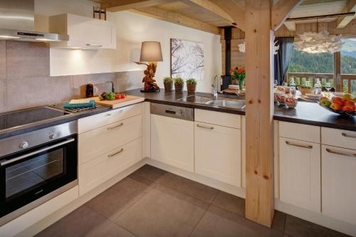 une cuisine avec des armoires blanches et un évier dans l'établissement Chalet Lydie Manigod - OVO Network, à Manigod