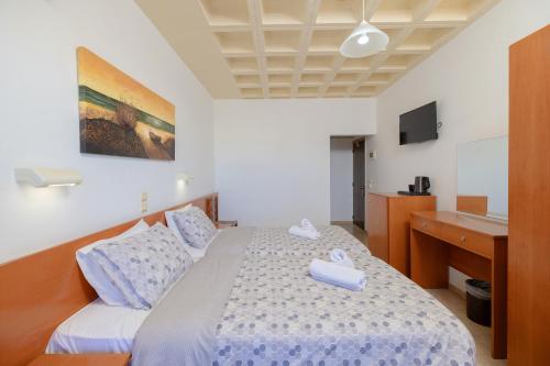 a bedroom with a bed with blue and white sheets at Heleni Beach Hotel in Ialyssos