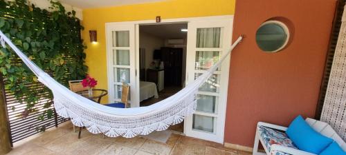 a hammock hanging in a living room with a room at Pousada Enseada do Gostoso in São Miguel do Gostoso