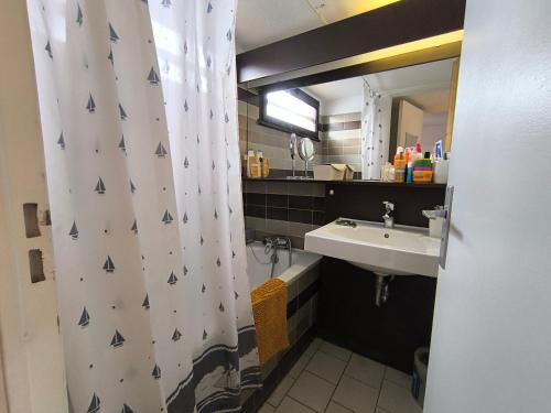 une salle de bain avec un lavabo et un rideau de douche dans l'établissement 5080 Hameau des pins 23, au Cap d'Agde