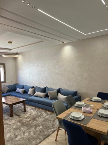 uma sala de estar com um sofá azul e uma mesa em Appartement safran avec piscine em Marraquexe
