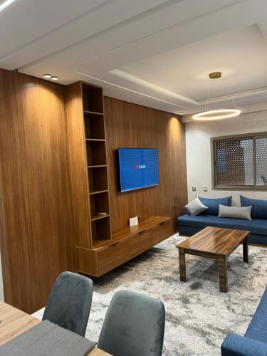 uma sala de estar com um sofá azul e uma TV em Appartement safran avec piscine em Marraquexe
