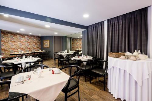 a dining room with white tables and black chairs at Elina Hotel Apartments in Rethymno Town
