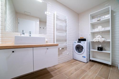 a white bathroom with a washing machine and a sink at GALANDA APARTMENTS in Turčianske Teplice
