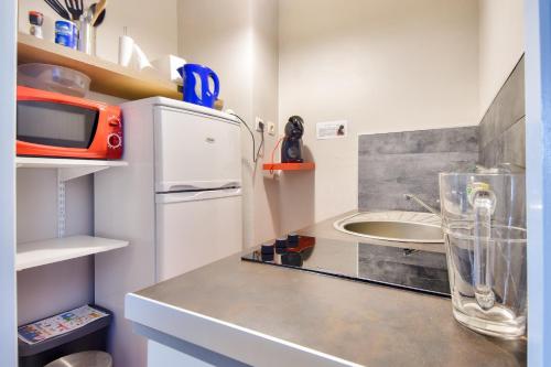 une cuisine avec un réfrigérateur blanc et un évier dans l'établissement Douce échappée à deux pas de la plage, à Saint-Hilaire-de-Riez