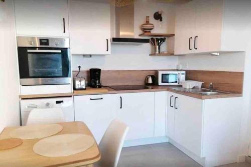 a kitchen with white cabinets and a wooden table at Maisonnette pour 2 personnes - Vue mer - Plage à 100 mètres in Ploubazlanec
