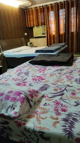 Hotel plaza في Rohtak: سريرين في غرفة في الفندق مع غطاء سرير من الزهور