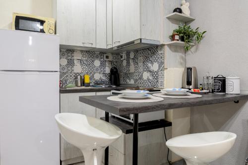une cuisine avec un comptoir et 2 chaises blanches dans l'établissement CityScape Studio, à Alexandroúpolis