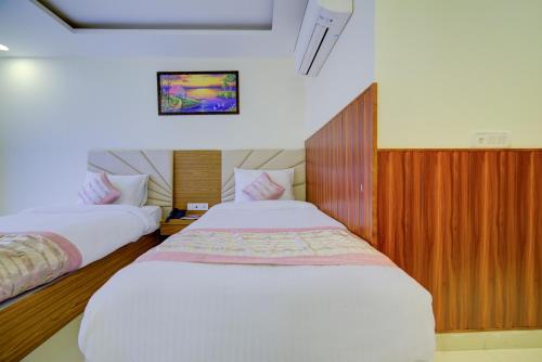 a bedroom with two beds and a tv on the wall at Hotel Grand Suites By D'Capitol Near IGI Airport in New Delhi