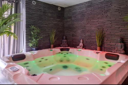 bañera rosa en una habitación con plantas en L'escapade, en Auriol