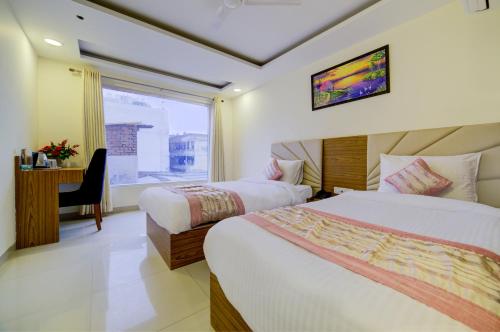 ニューデリーにあるGrand Suites Hotel By D Capitol- Mahipalpur,Delhi Airport, Aerocityのベッド2台、デスク、窓が備わるホテルルームです。