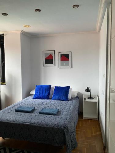 - une chambre avec un lit et des oreillers bleus dans l'établissement Apartamento en Gijon, à Gijón