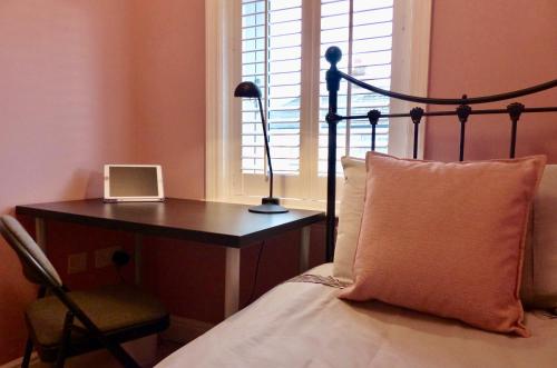1 dormitorio con 1 cama y escritorio con lámpara en The Sanctuary, en Richmond