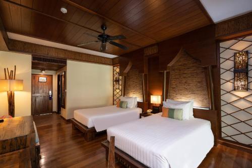 een slaapkamer met 2 bedden en een plafondventilator bij Centara Koh Chang Tropicana Resort in Ko Chang