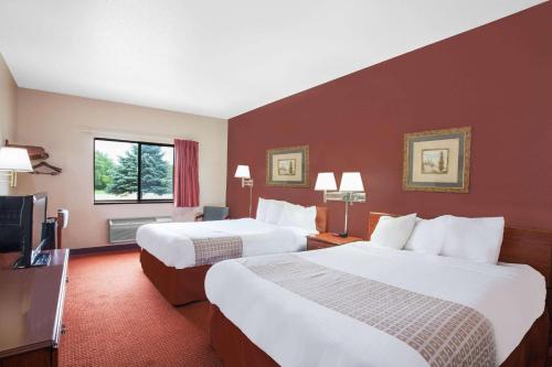 a hotel room with two beds and a flat screen tv at Super 8 by Wyndham Mason City in Mason City