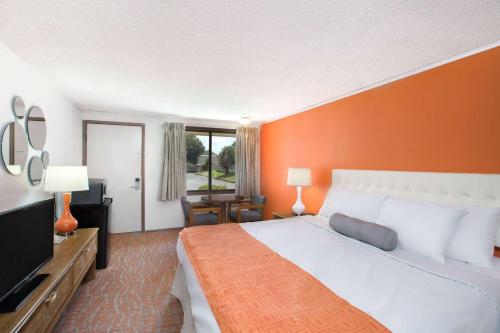 a bedroom with a large bed with an orange wall at Howard Johnson by Wyndham Wilmington in Wilmington