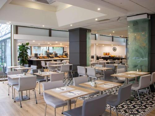 une salle à manger avec des tables et des chaises ainsi qu'un restaurant dans l'établissement Mercure Paris Centre Tour Eiffel, à Paris