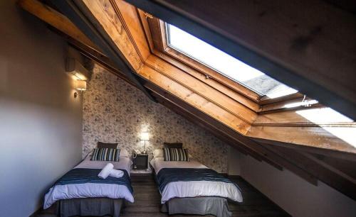 a attic room with two beds and a skylight at Rustik Hostal Rural in Molinaseca