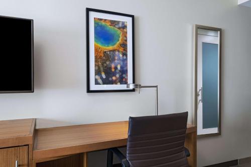 a desk with a chair and a painting on the wall at Hyatt Place Greensboro Downtown in Greensboro