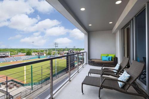 a balcony with chairs and a view of a baseball field at Hyatt Place Greensboro Downtown in Greensboro