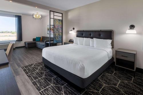 a bedroom with a large bed and a living room at La Quinta Inn & Suites by Wyndham Maricopa Copper Sky in Maricopa