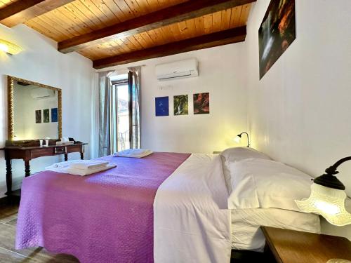 a bedroom with a bed with a purple blanket at Casa le Maioliche by Housilia in Cefalù