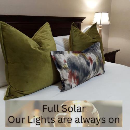 a bed with green pillows and a sign saying full solar our lights are always at Aloes Guest House 62 on Meintjies in Middelburg