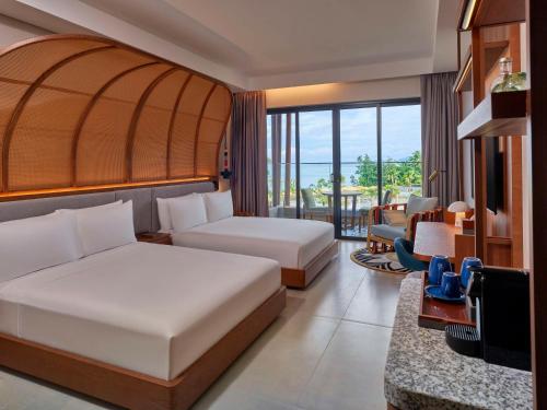 a hotel room with two beds and a desk at Canopy By Hilton Seychelles in Anse a La Mouche