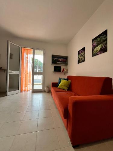sala de estar con sofá rojo y puerta abierta en Sole&Mare, en Villaggio Azzurro