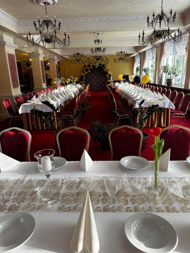 una fila de mesas en una habitación con sillas rojas en Hotel Koch, en Kętrzyn