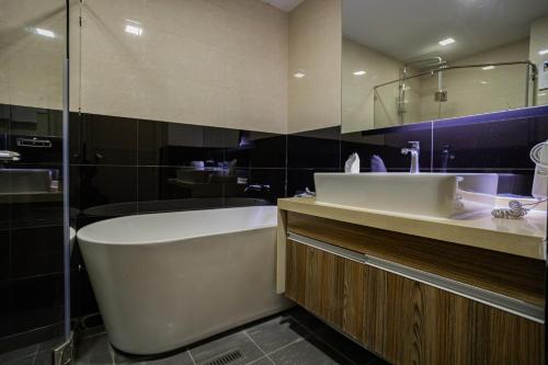 a bathroom with a tub and a sink and a shower at Ramada Ekamai in Bangkok