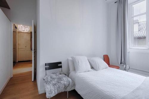 ein weißes Schlafzimmer mit einem Bett und einem Stuhl in der Unterkunft T3 hypercentre proche gare in Bourgoin