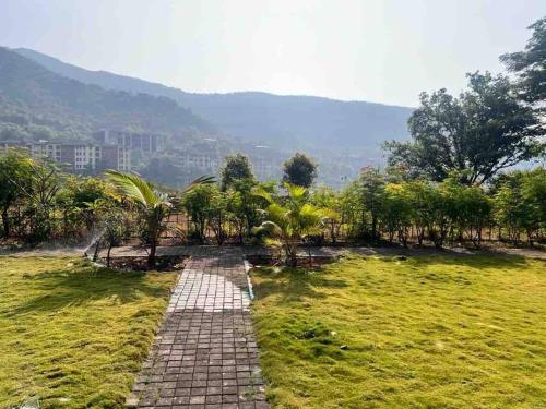 a brick path in a field with a mountain in the background at Endora homestay - A fully equipped lake-facing 3BHK in Lavasa