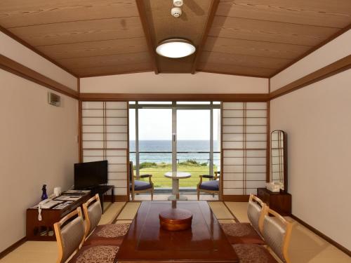 a room with a table and chairs with a view of the ocean at Shimoda Prince Hotel in Shimoda