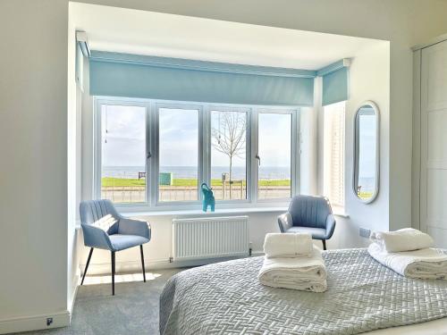 a bedroom with a bed and two chairs and a window at Shoreside Villa, by the Golf Course in Bridlington