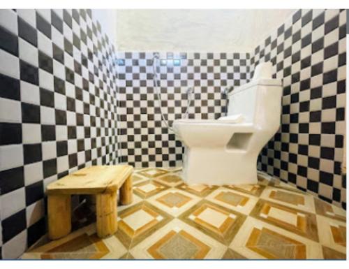 a checkered bathroom with a toilet and a wooden stool at Chalo Daanda Forest Farm, Chamba in Chamba