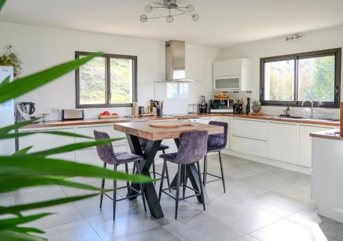 a kitchen with a wooden table and purple chairs at Sunset Villa - La maison des couchers de soleil in Villaz