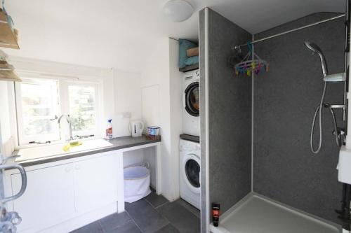 a bathroom with a shower and a sink and a washing machine at Secluded woodland annex between Mylor and Flushing in Falmouth