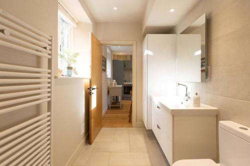 a bathroom with a sink and a toilet and a hallway at Secluded woodland annex between Mylor and Flushing in Falmouth