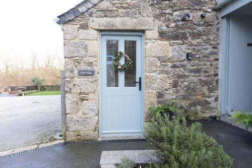a stone house with a white door with a wreath at Secluded woodland annex between Mylor and Flushing in Falmouth